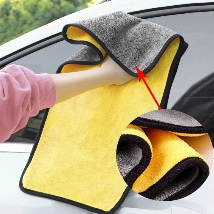 Yellow and gray microfiber cleaning towel with a red arrow pointing to a feature, used on a car window.