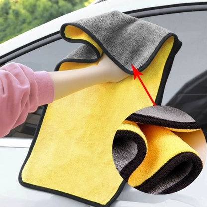 Yellow and gray microfiber cleaning towel with a red arrow pointing to a feature, used on a car window.
